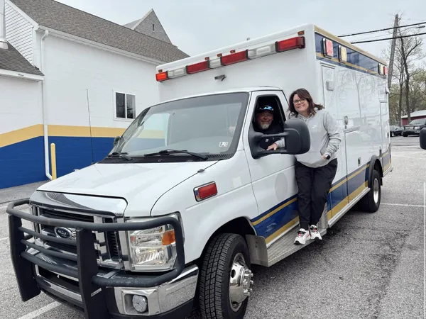 The whole truck in a parking lot, the day the owners bought it: one at the wheel, the other standing on the step